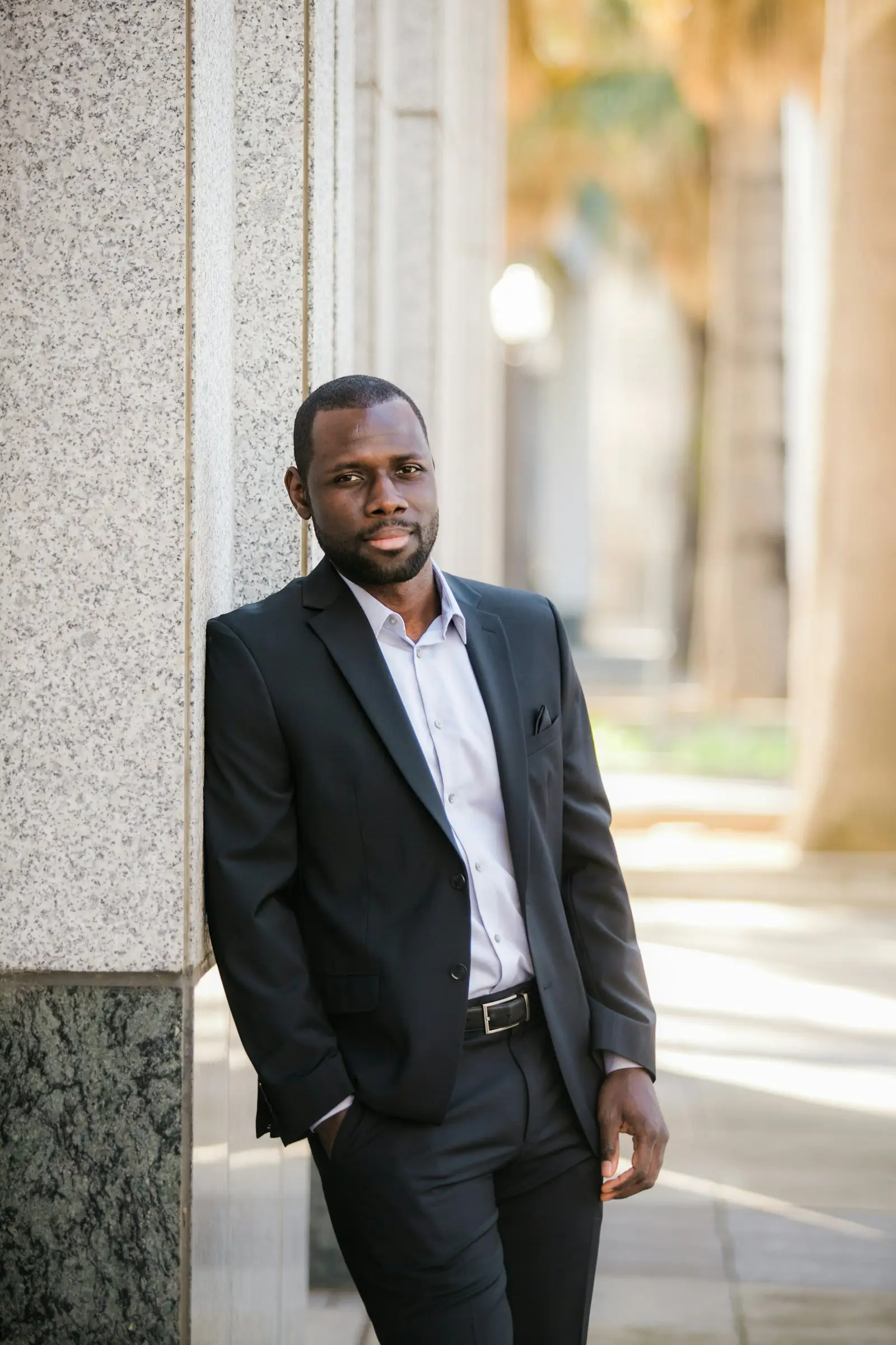 A man in a dark suit standing outside an office building